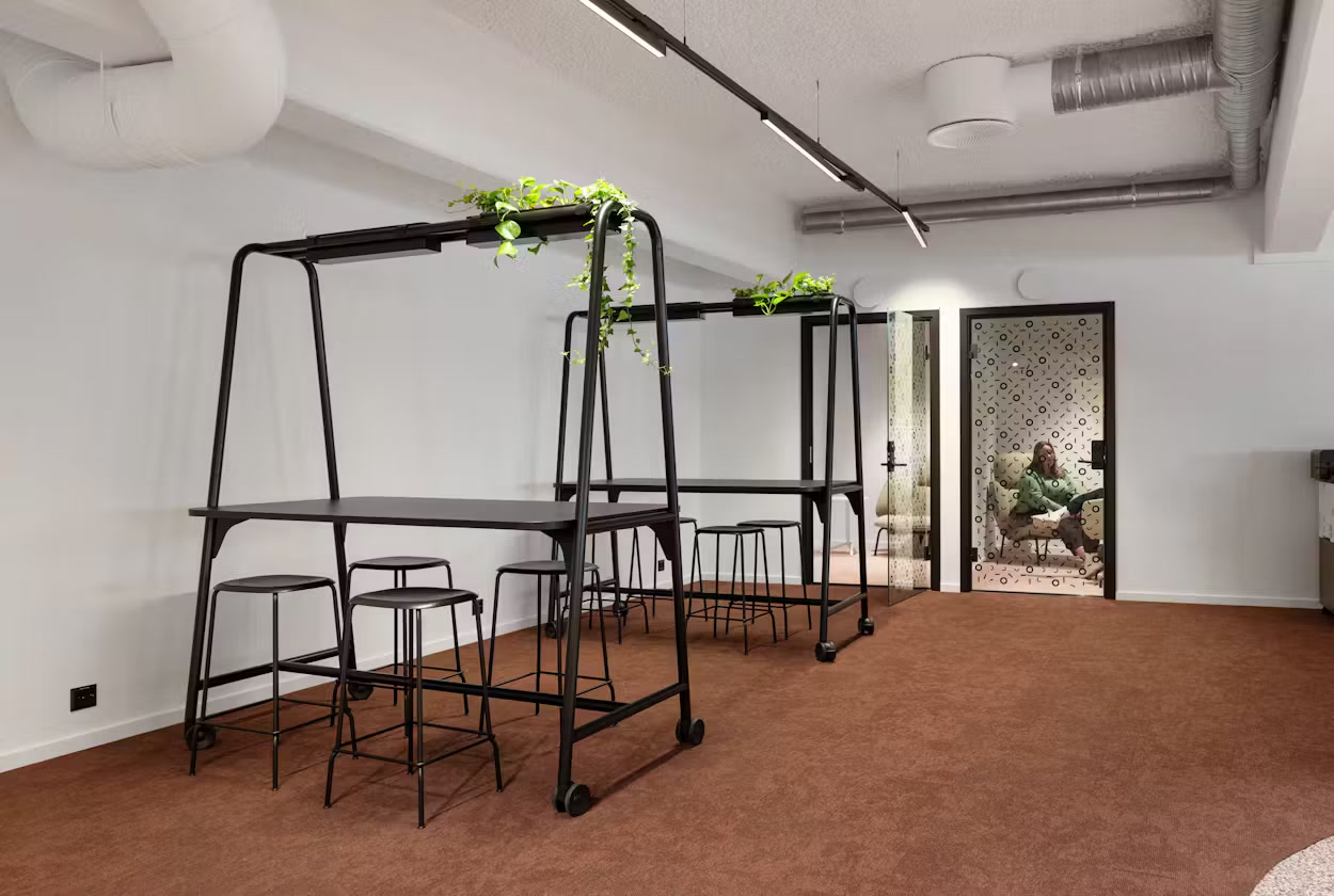 Åpent arbeidsområde med ståbord, planter og stillerom i Silvercons lokaler